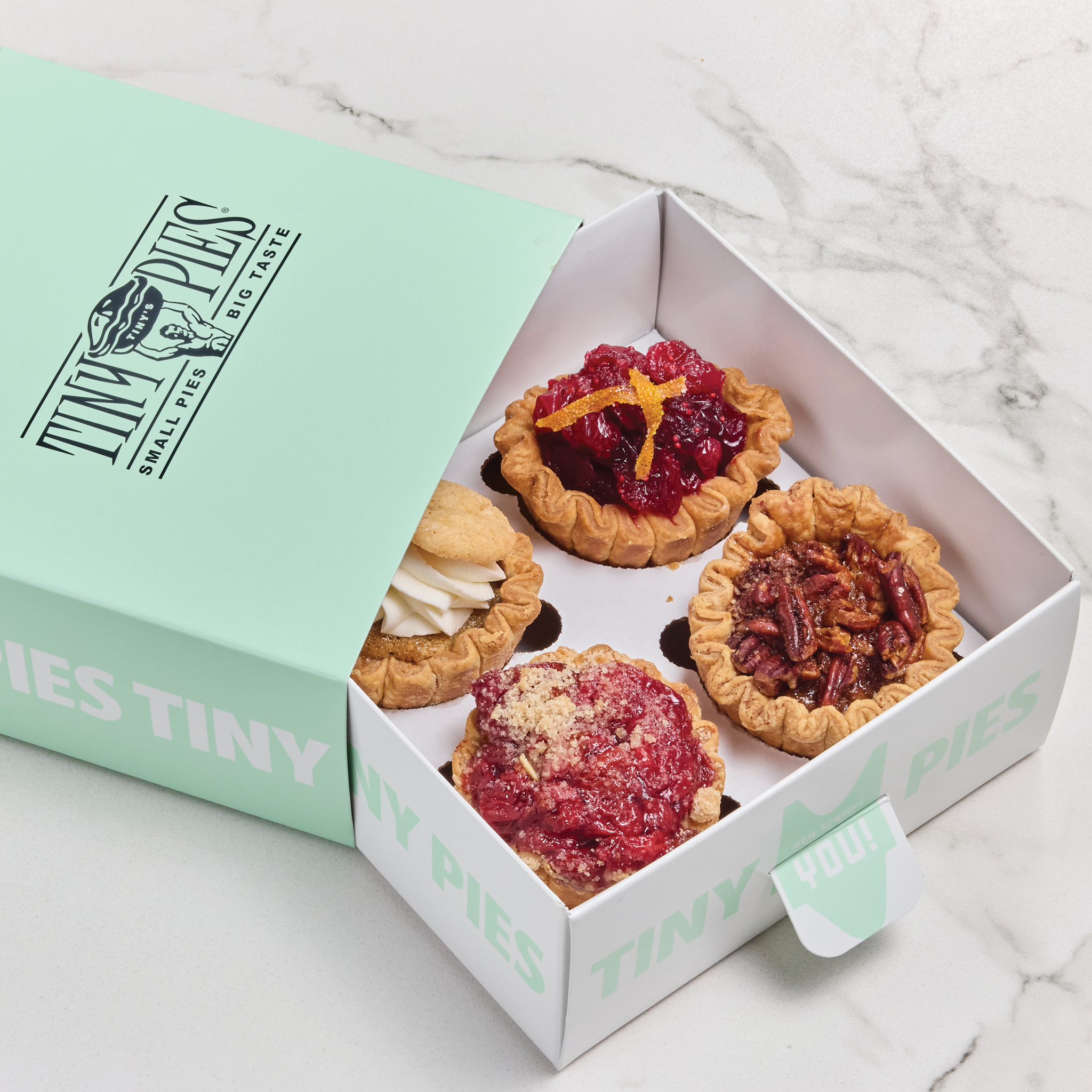 Four holiday mini pies: cherry, pecan, snickerdoodle and cranberry orange in a mint green gift box